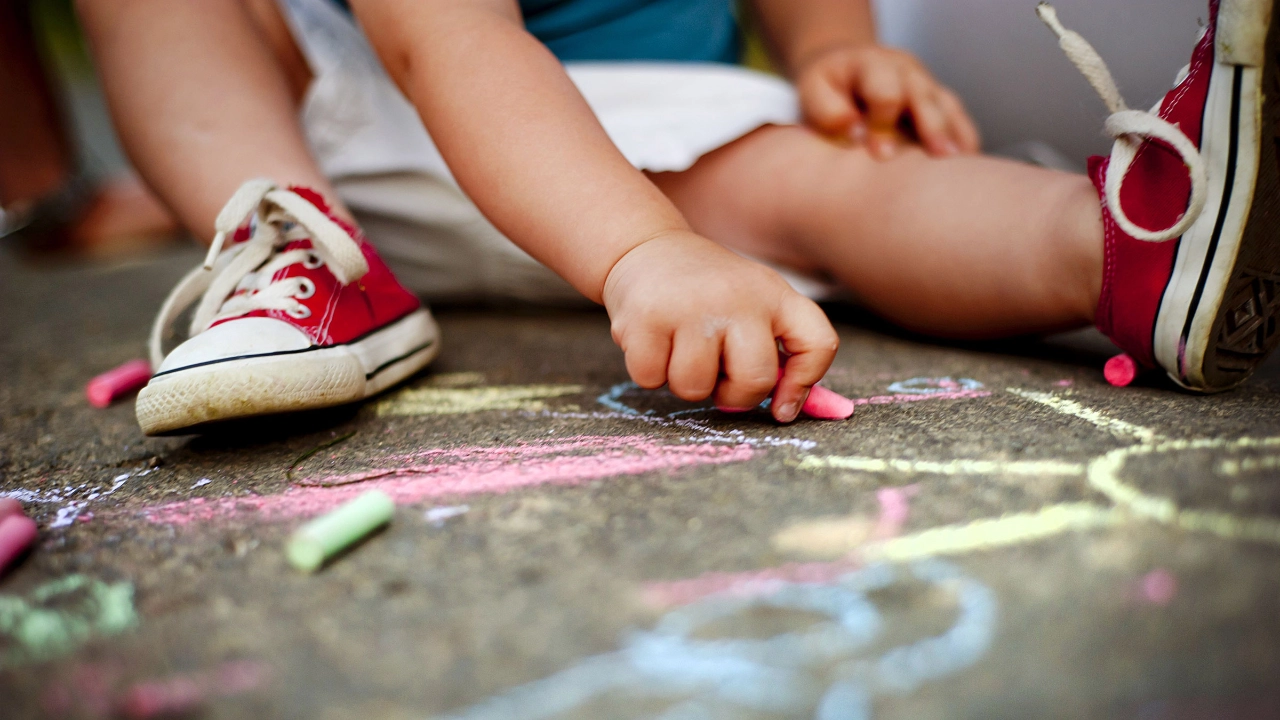 Kind malt mit Kreide auf dem Asphalt