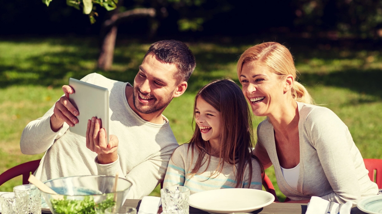 Familie sitzt mit einem Tablet im Garten